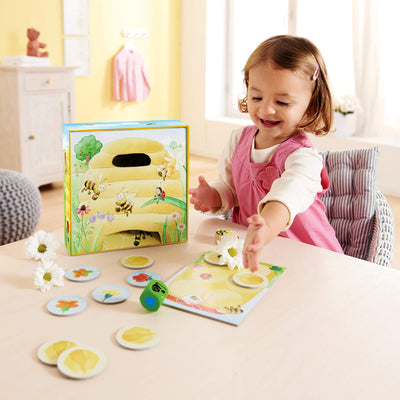 Girl rolling green wooden die playing Hanna Honeybee from HABA