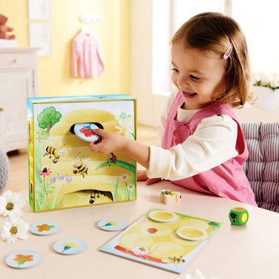 Girl smiling putting round flower game piece into the beehive