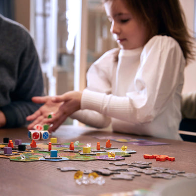 Girl rolling dice playing King of the Dice Board Game
