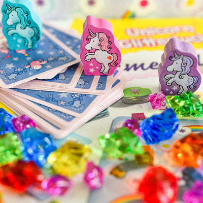 Colorful unicorn-themed game pieces including cards and gems on a Unicorn Glitterluck - Game Collection game box