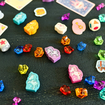 Colorful gemstone-like game pieces on a dark surface from the game Unicorn Glitterluck - Game Collection
