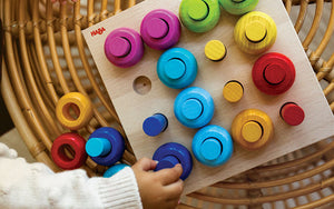 Close up of a child's hand playing with HABA Wooden Pegging Game