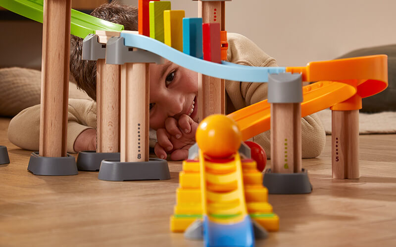 Boy laying on the ground looking at the camera through the Kullerbu Melody Dominoes Set