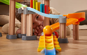 Boy laying on the ground looking at the camera through the Kullerbu Melody Dominoes Set