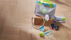 Children’s Doctor Play Set items and a toy Kullerbu car on a wooden floor.