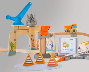 Toy construction playset with crane, trucks, tracks, and traffic cones.