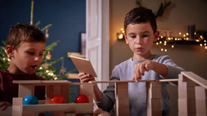 Two boys playing with HABA wooden blocks in a room decorated for Christmas