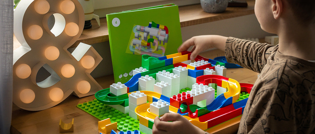 Child playing by a window with Hubelino Marble Run track set