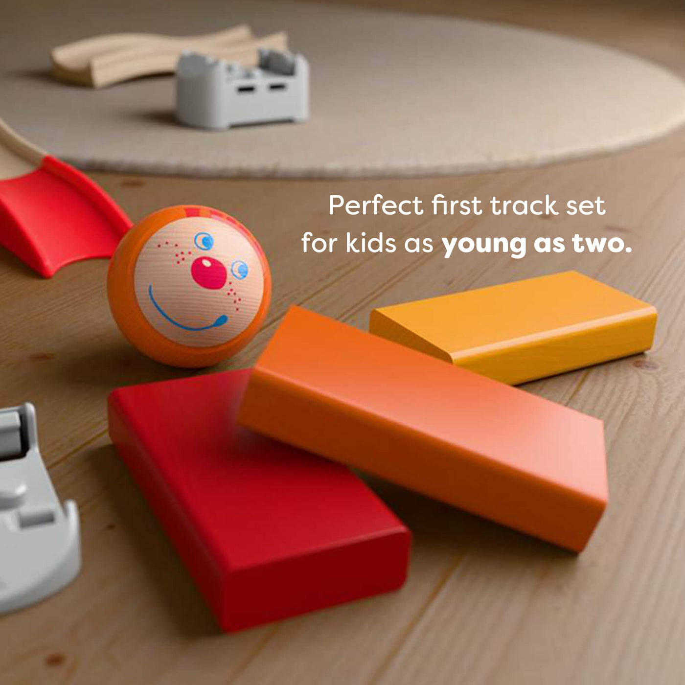 Colorful toy track set on a wooden surface with text reading 'Perfect first track set
for kids as young as two.'