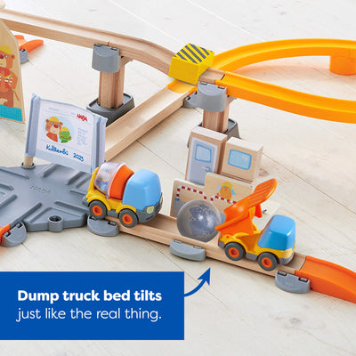 Toy construction set with tracks, one cement mixer and one dump truck with tiling bed on a light surface