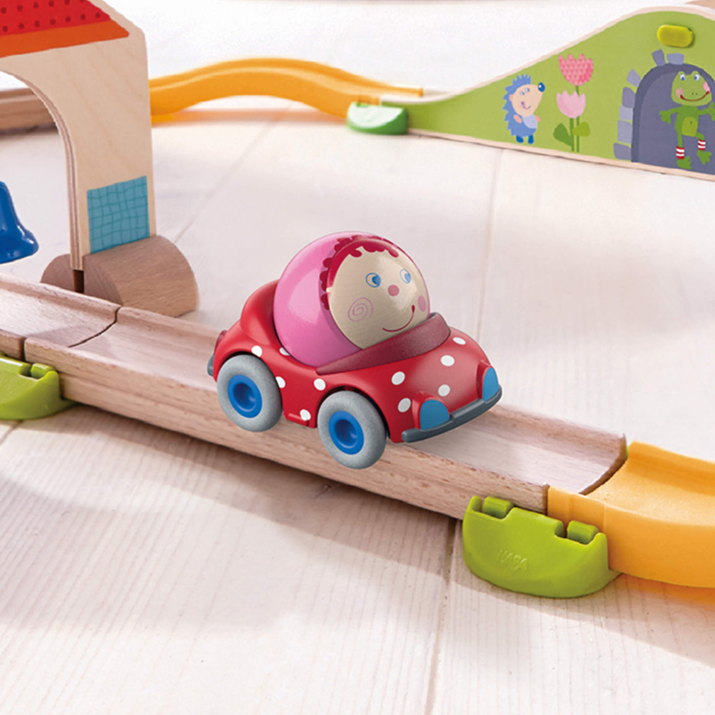 Toy car on a wooden track with colorful accessories on a light background