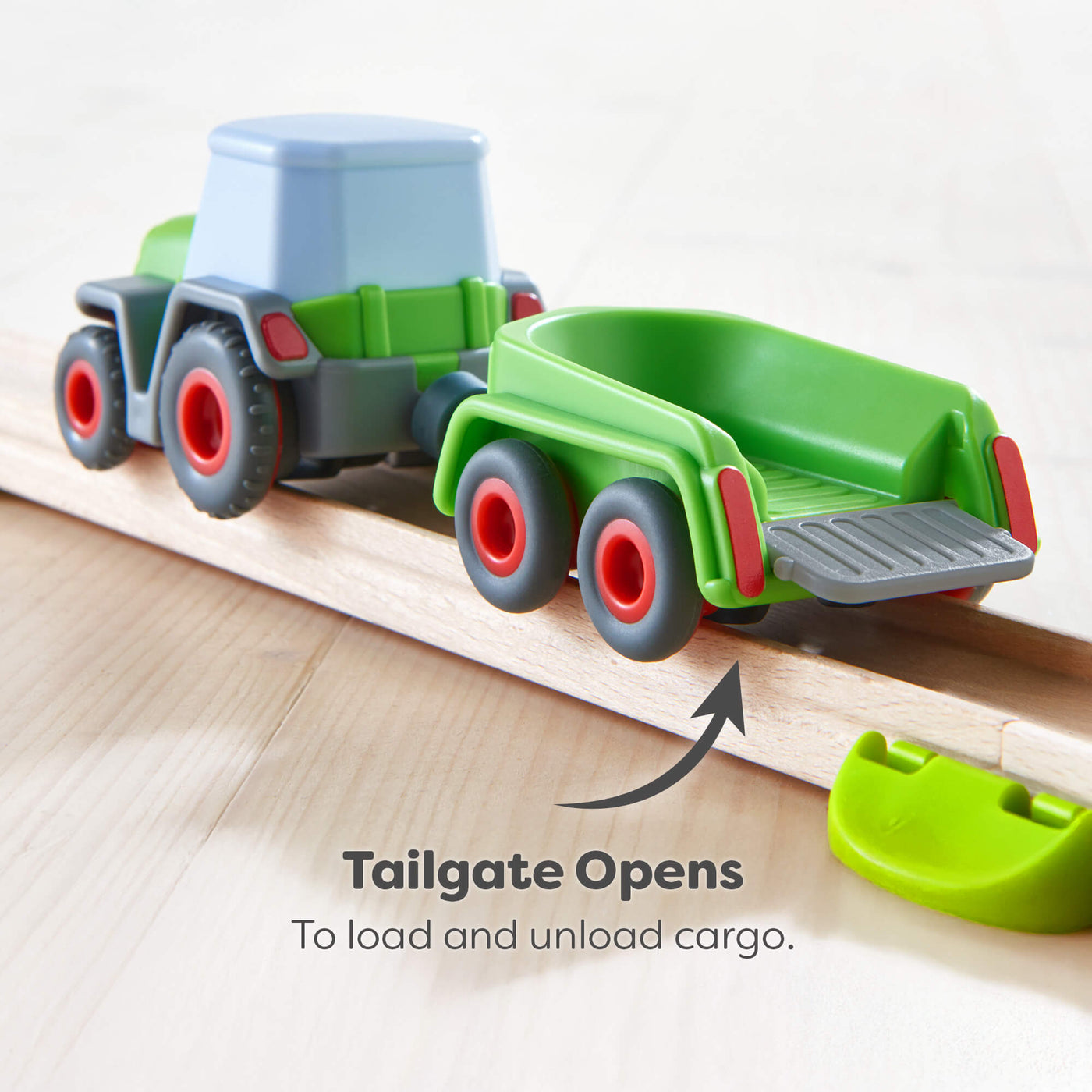 Toy truck with a green trailer on a wooden track, showing how to open the tailgate.