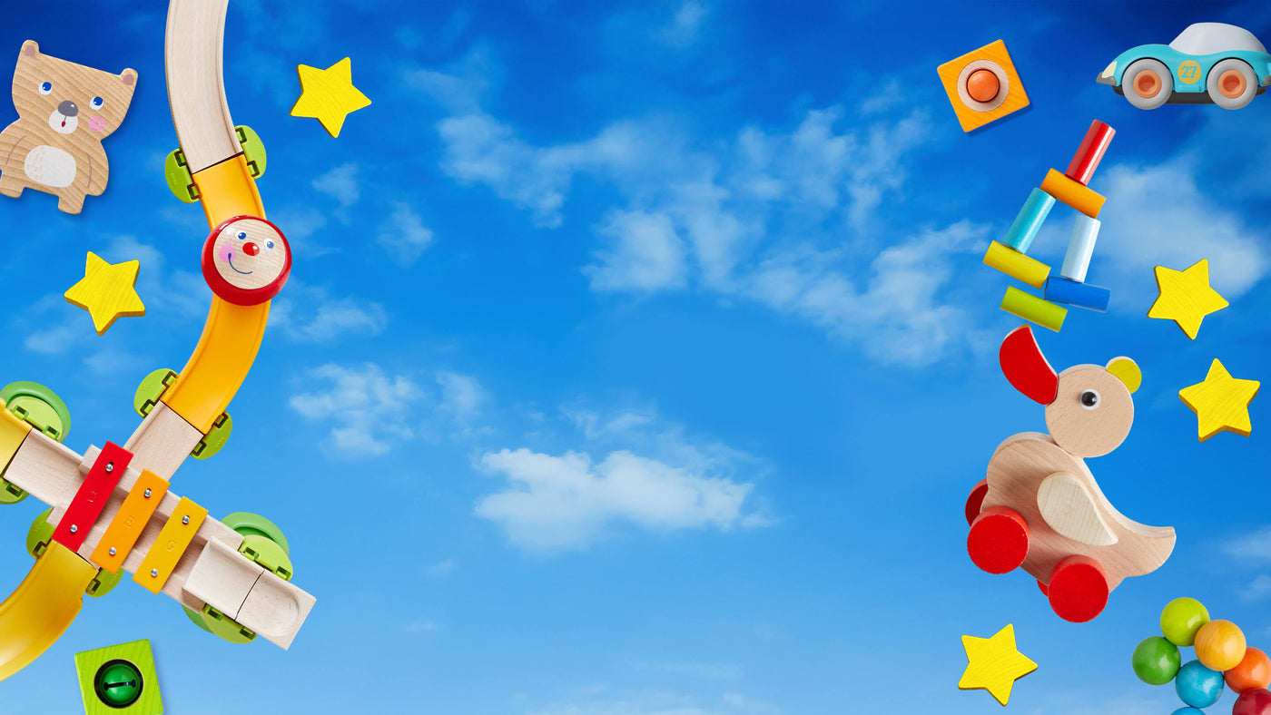A vibrant and playful arrangement of children's toys against a clear blue sky with scattered white clouds.