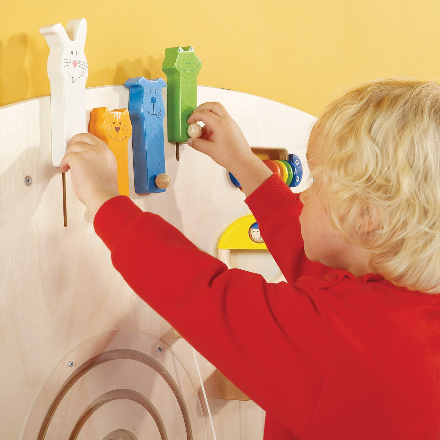 A child moving the sliding animal figures on the HABA Sensory Learning Wall Panel 