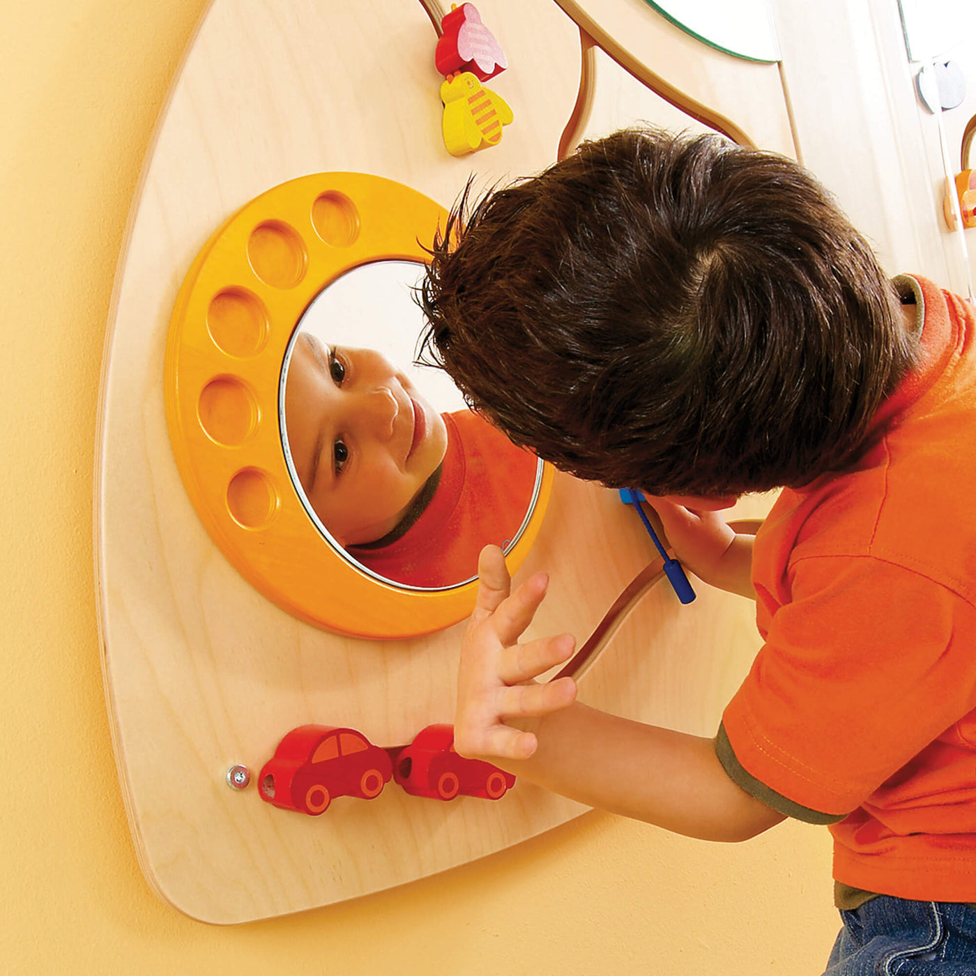 Child looking into a circular mirror on the HABA Sensory Learning Wall Panel 