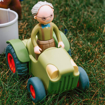 Close up of a toy farmer in a Little Friends Tractor outside on the grass