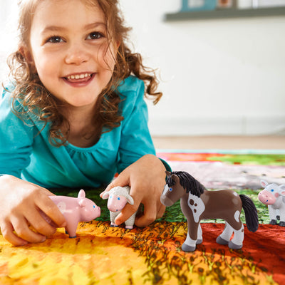 Child playing with Little Friends toy farm animals on a colorful surface