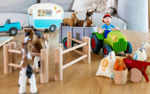 Closeup of HABA Little Friends tractor, horses, wheelbarrow, and camper