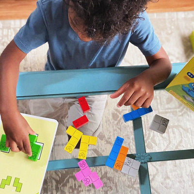 Overhead view of a boy playing Happy Worms by placing a green wooden worm on the template surrounded by colorful wooden worms