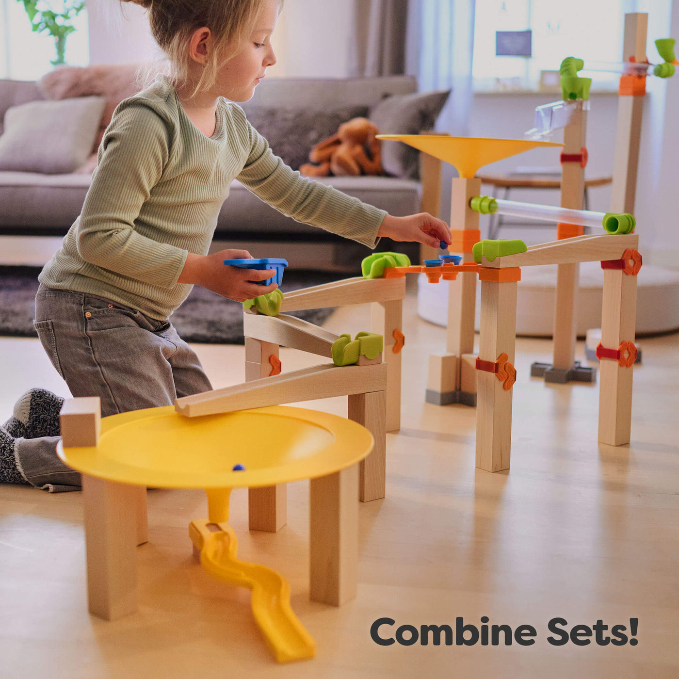 Young girl playing with Marble Run Funnel Jungle Starter Set on living room floor