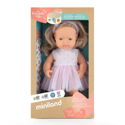 Miniland Realistic Montessori Doll with blonde hair and blue eyes, wearing a lavender polka dot top and pale pink tulle skirt with a matching headband, standing up in the box she is packaged in.
