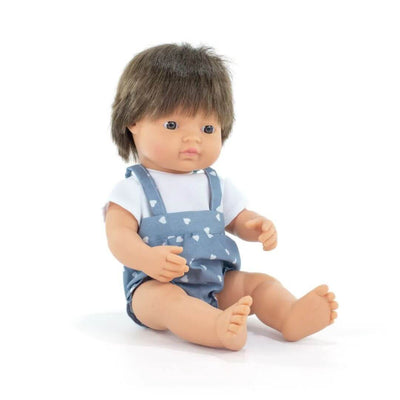 A realistic white boy doll with brown hair, dressed in a light blue romper with white heart patterns, sitting upright against a white background.