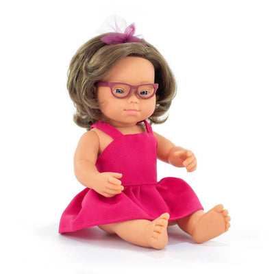 iniland realistic Montessori girl doll with Down syndrome, wearing glasses and a bright pink dress with a tulle bow headband, seated against a white background.
