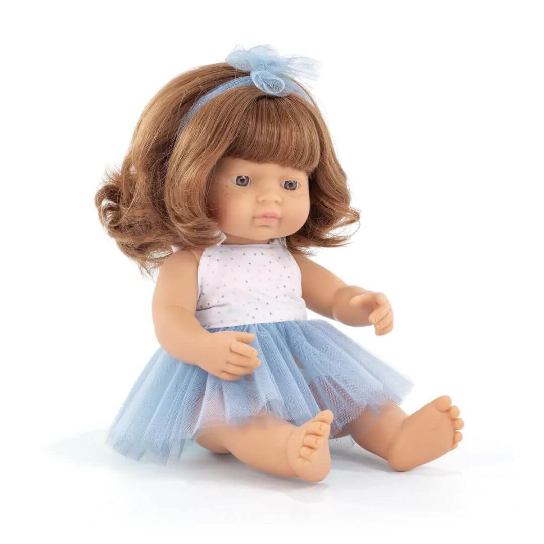 Miniland Montessori red-haired girl doll wearing a blue tulle skirt and white top with matching bow, seated on a white background.