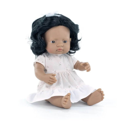 Miniland Montessori Hispanic girl doll with dark curly hair, wearing a white dress with a bow, seated on a white background.