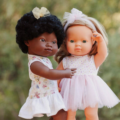 Two Miniland realistic Montessori dolls,  standing together outdoors.