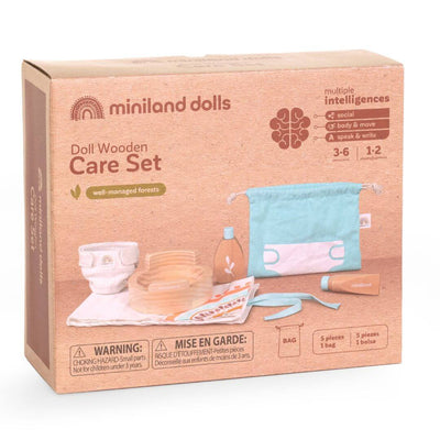 The box that this wooden doll care set by Miniland comes in, featuring a doll potty, wooden lotion bottle, soap, fabric changing mat, washcloth, and a storage bag, made from FSC-certified sustainable wood for nurturing pretend play.