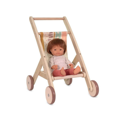 Wooden doll stroller by Miniland, made in Spain from sustainable wood with a colorful fabric seat—with a Miniland doll with short brown hair and wearing a sweater and orange knit pants.