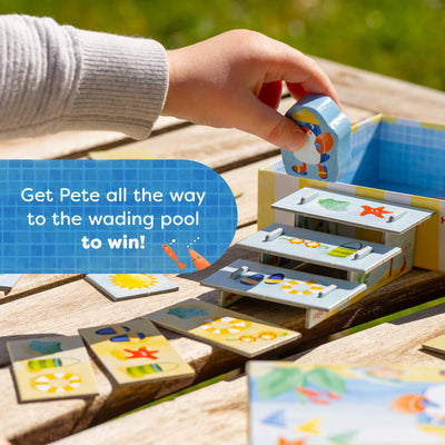 Child playing with My Very First Games To Go - Pete Ahoy! on a wooden surface with text reading 'Get Pete all the way to the wading pool to win!'