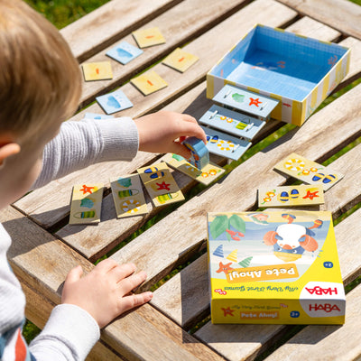 Child playing with My Very First Games To Go - Pete Ahoy! on a wooden table outdoors