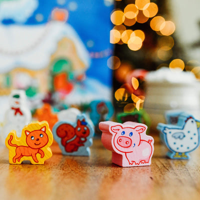 Close up of a wooden orange cat, squirrel, pig and chicken with blurry Christmas lights in the background