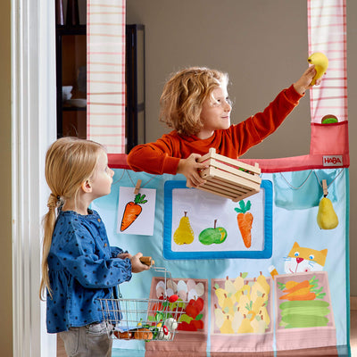 Kids with wooden box of fruits and HABA Hanging Doorway Play Store