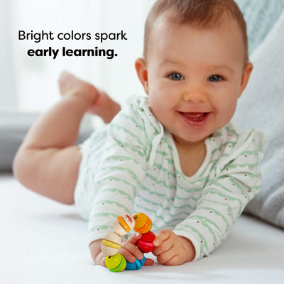 Baby playing with a colorful Rainbow Rattle Grasping and Teething Toy, smiling, with text 'Bright colors spark early learning.'