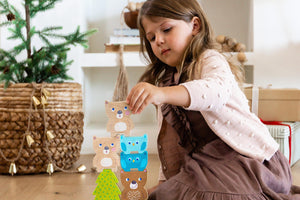 Girl in a holiday setting stacking wooden bears from Forest Friends Stacking Toy