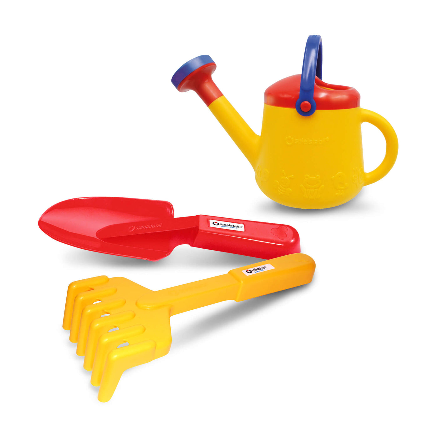 A set of colorful Spielstabil plastic toy gardening tools including a red shovel, yellow rake, and a yellow watering can with a red top.