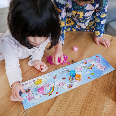 Overhead view of two girls at a table holding a die playing Unicorn Glitterluck Cloud Crystals game