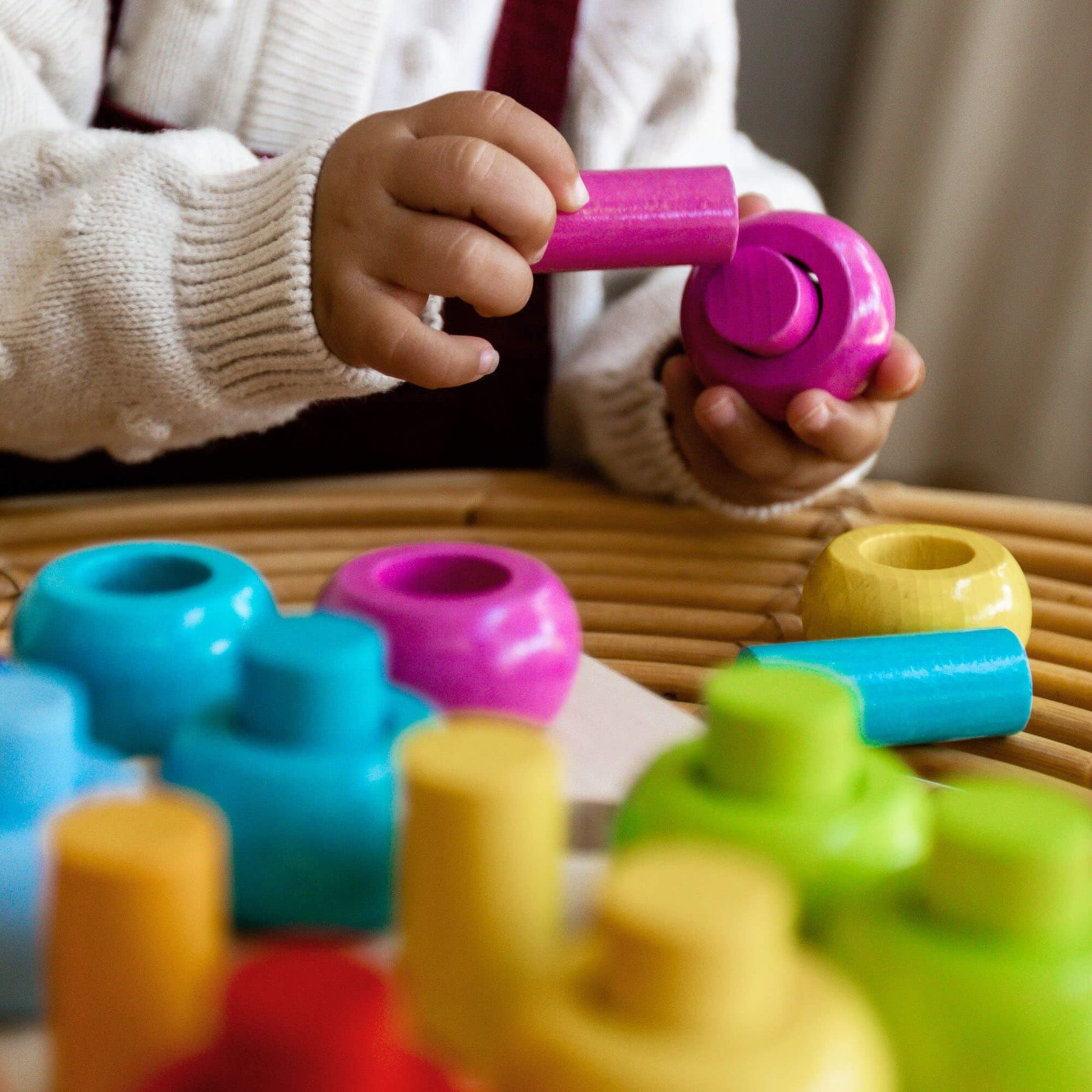Toddler hands playing with Rainbow Whirls Pegging Game 