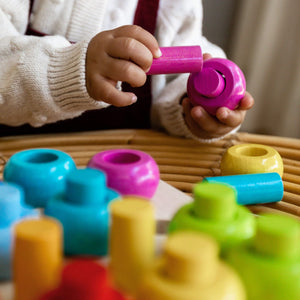 Toddler hands playing with Rainbow Whirls Pegging Game 